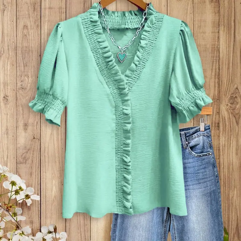 A bright pink V-neck shirt with ruffled details, featuring pleats at the cuffs and front, made of soft fabric.