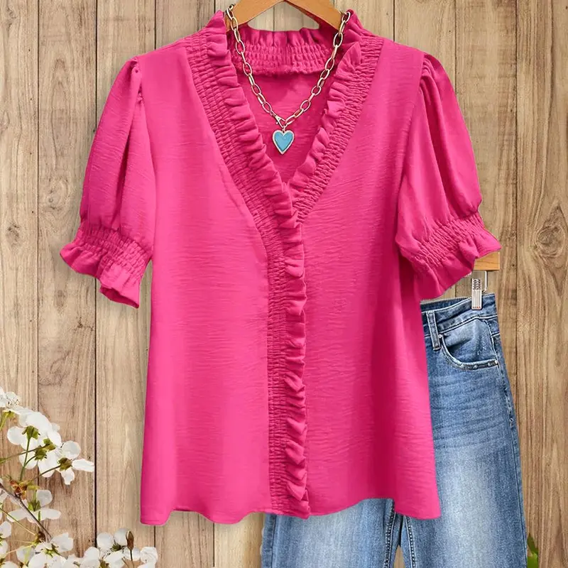 A bright pink V-neck shirt with ruffled details, featuring pleats at the cuffs and front, made of soft fabric.