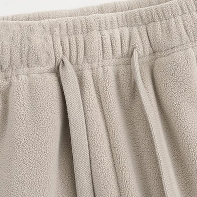 Unisex fleece-lined sweatpants with brushed interior, flat front design, zippered pockets, and a relaxed fit