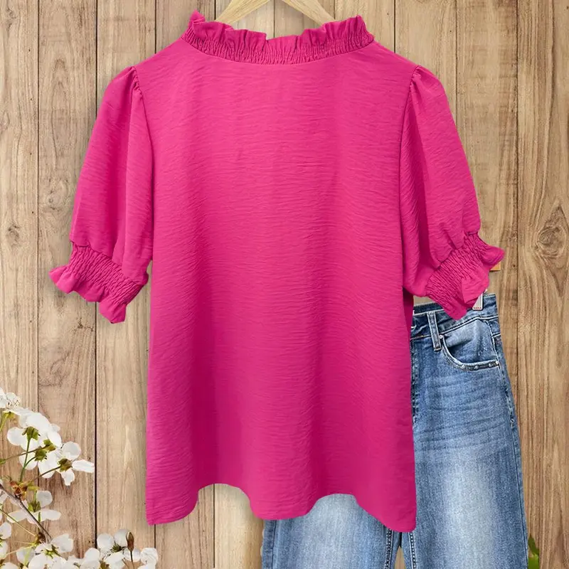 A bright pink V-neck shirt with ruffled details, featuring pleats at the cuffs and front, made of soft fabric.