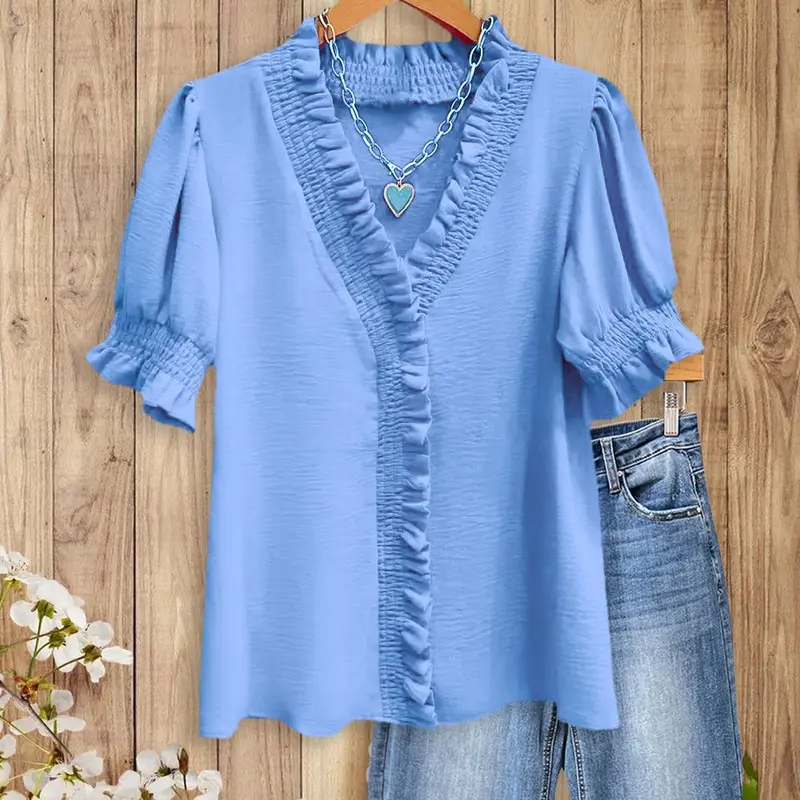 A bright pink V-neck shirt with ruffled details, featuring pleats at the cuffs and front, made of soft fabric.